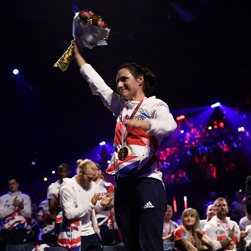 A paralympian proudly holds flowers up high at the Paralympics Team GB's homecoming event at AO Arena.